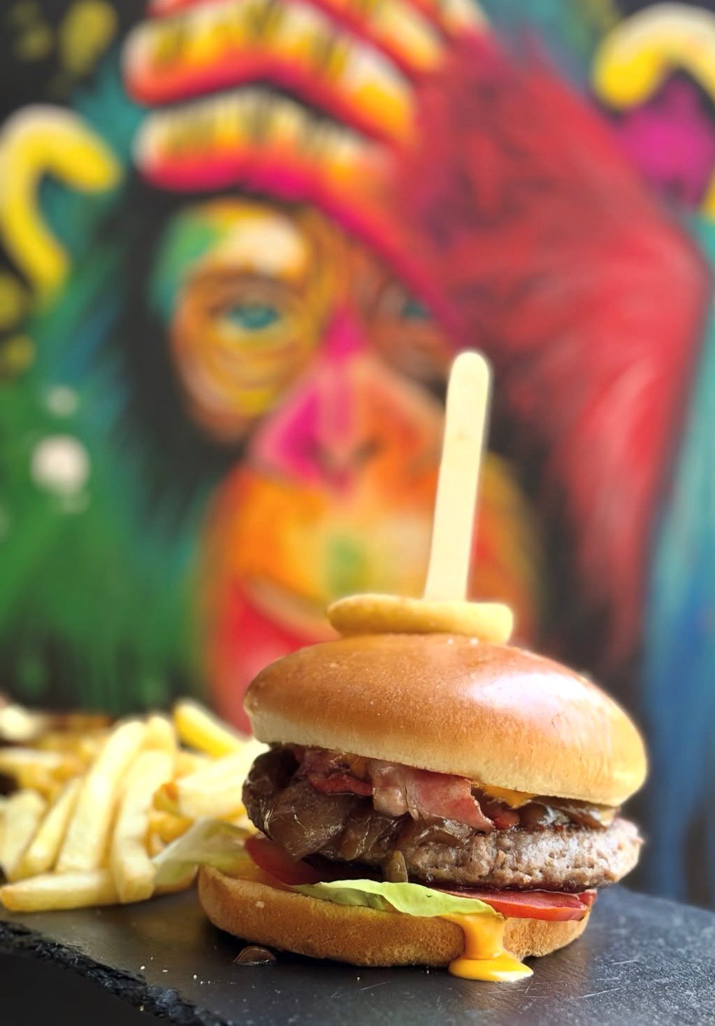 Signature burger and fries at Gorila Pub, with the pub's mural in the background