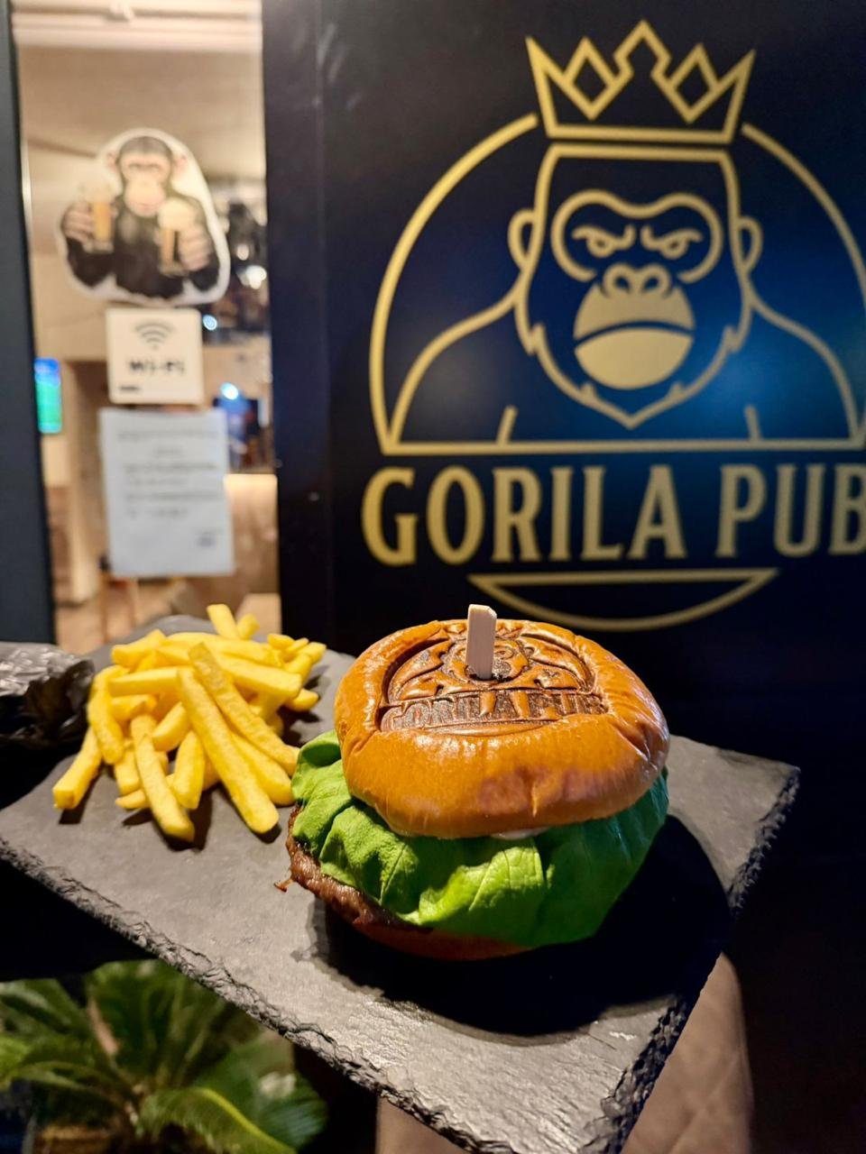 Gorila Pub signature burger and fries in front of the pub's neon sign